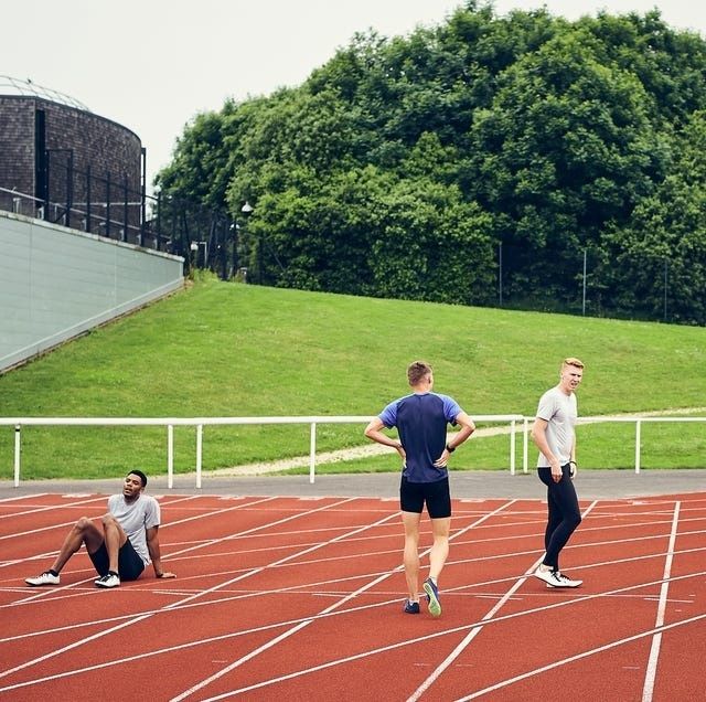 Three runners pause on a red athletics track after training
