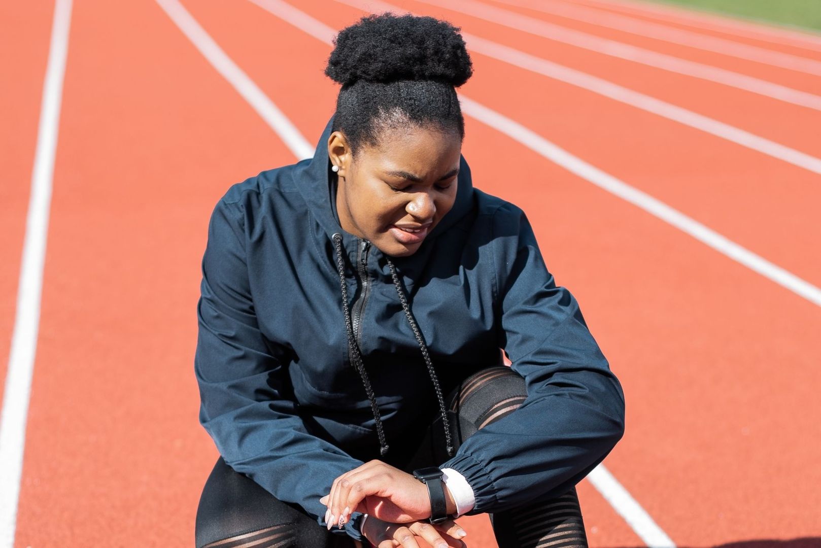 Athlete sitting on a track and looking at a smartwatch
